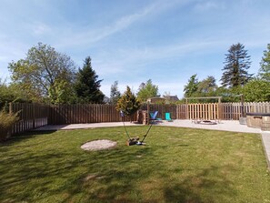 Ein Garten mit Holzzaun, Schaukel und Terrassenbereich.