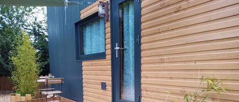 A modern wooden house with a deck, a window, and a door.