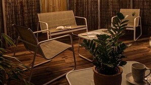 Una habitación con piso de madera, una planta en maceta sobre una mesa y dos sillas.