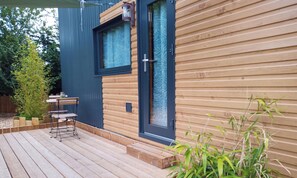 Ein modernes Holzhaus mit einer Terrasse, einem Fenster und einer Tür.