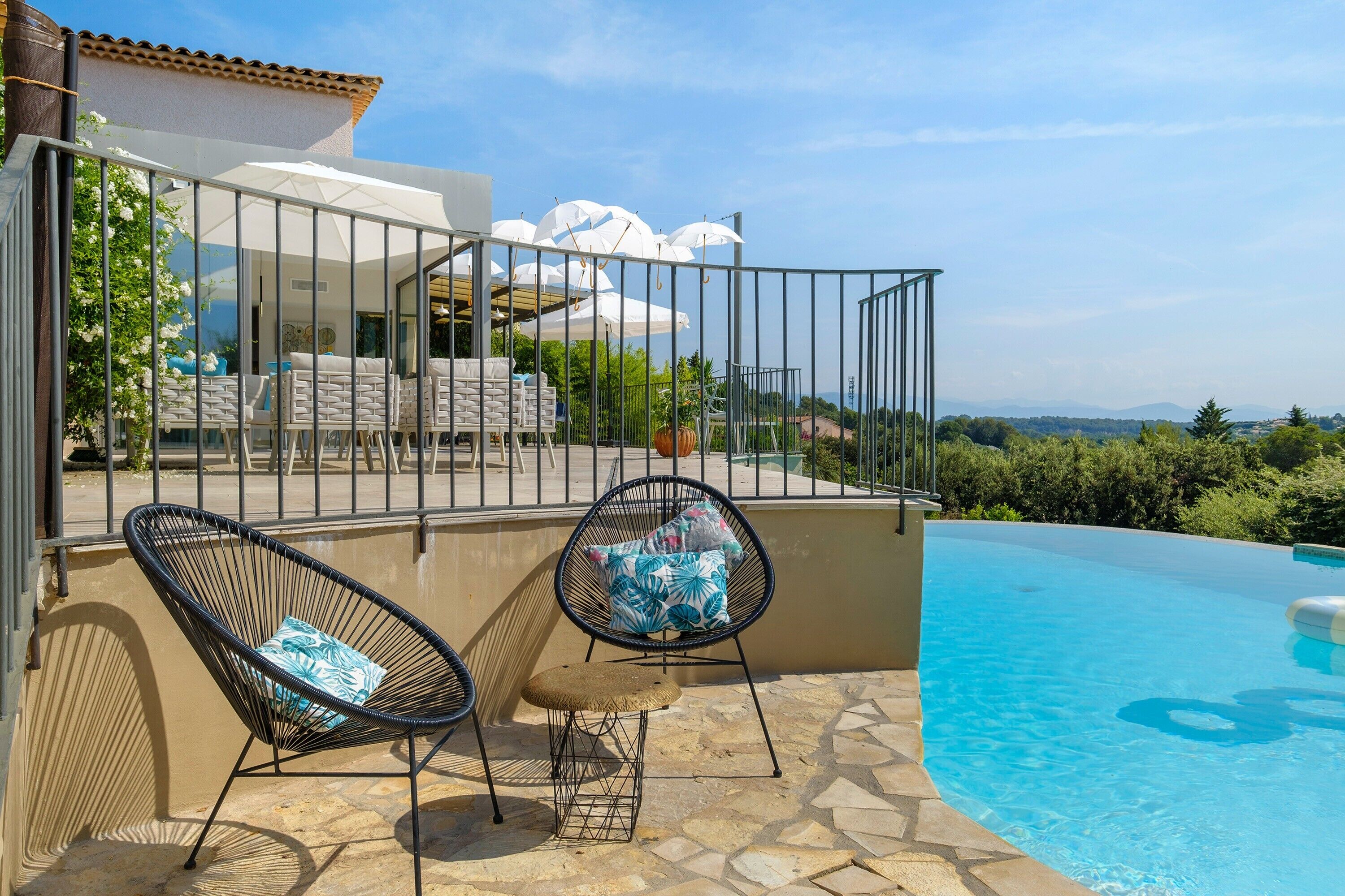 A poolside area with two lounge chairs, a small table, and a view of the pool and landscape.