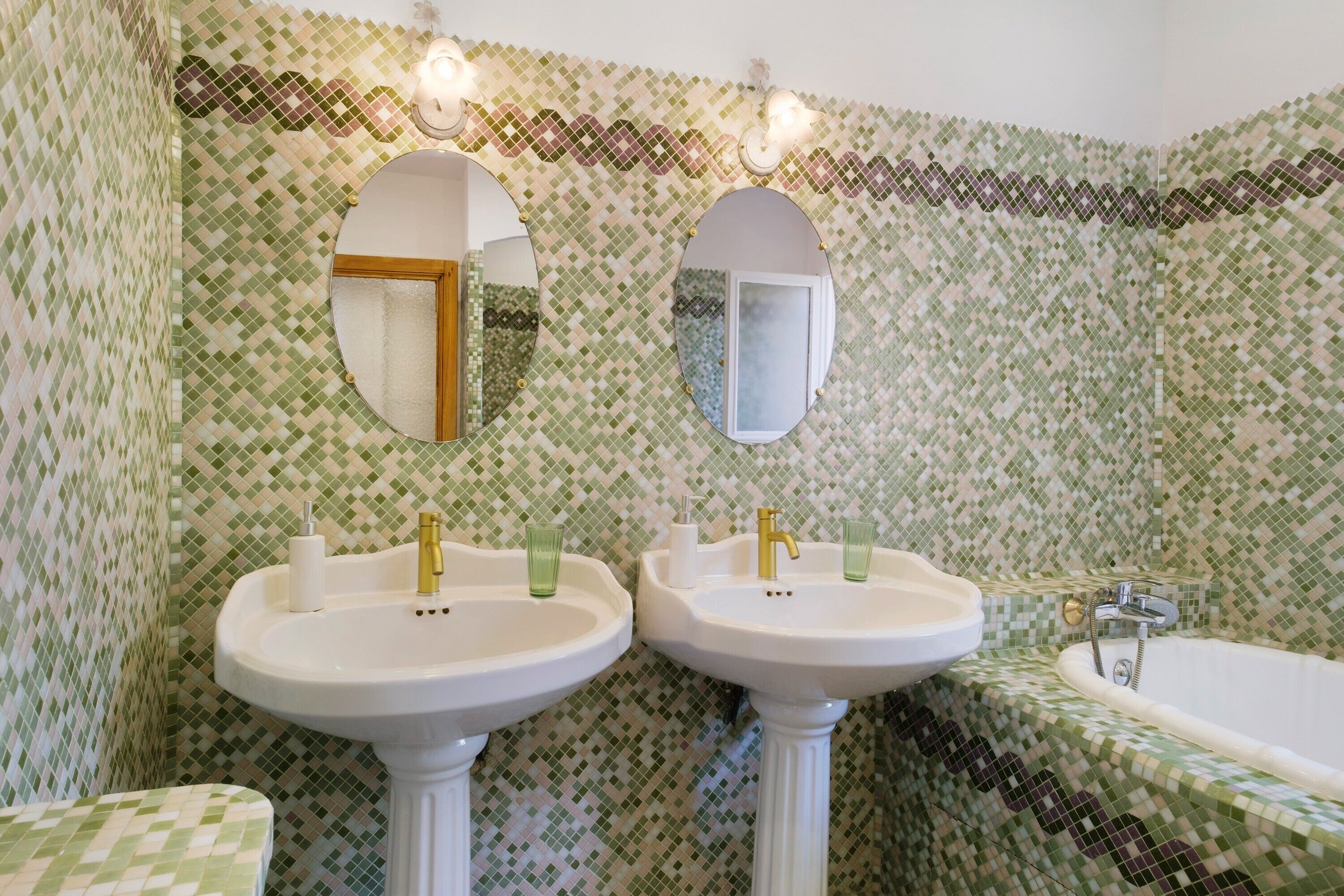 A bathroom with two sinks, a bathtub, and a mirror above each sink.