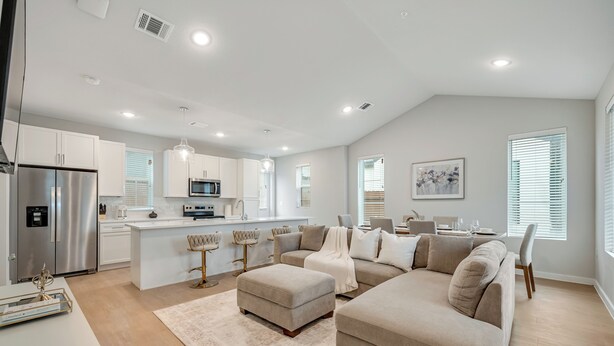 A modern kitchen with white cabinets, a stainless steel refrigerator, and a central island with seating.