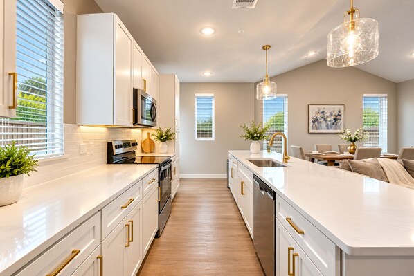 A modern kitchen with white cabinetry, stainless steel appliances, and a central island.