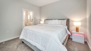 A bedroom with a large bed, bedside tables, a nightstand, and a mirror.