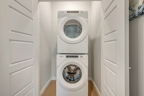 A compact laundry room with two stacked Whirlpool washing machines.