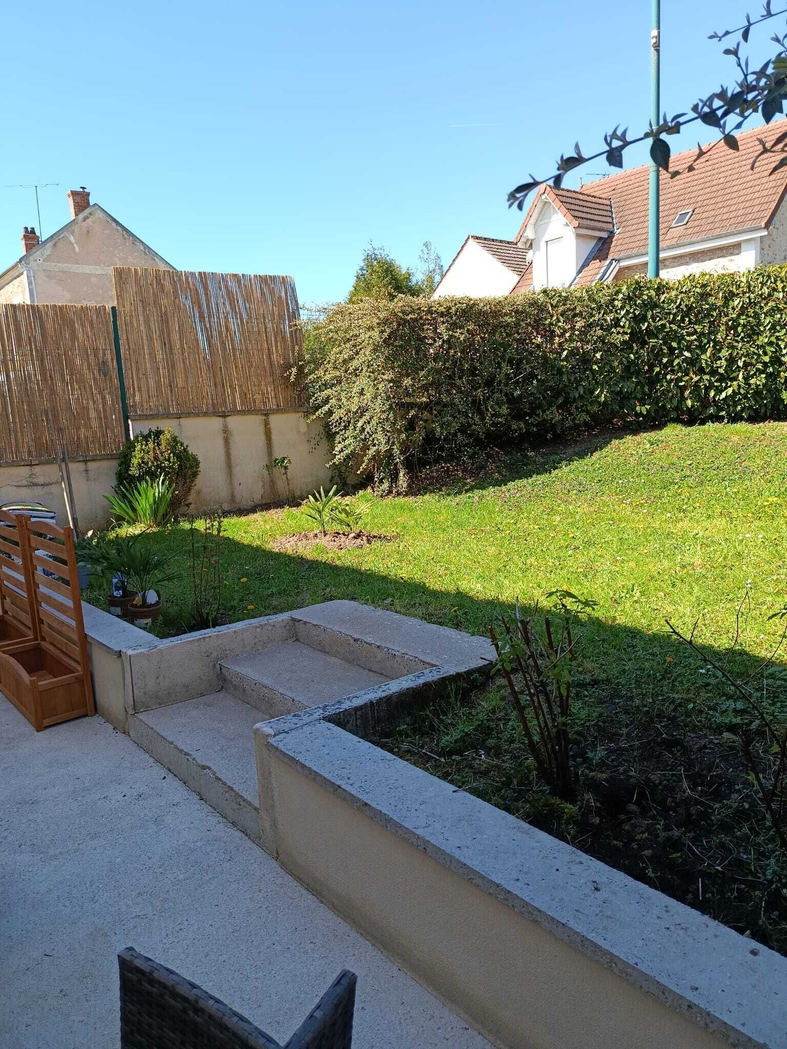 A residential backyard with a concrete staircase, a wooden bench, and a hedge.