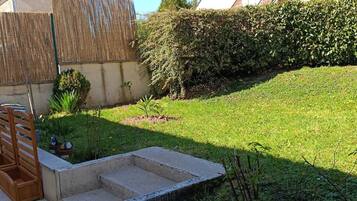 A residential backyard with a concrete staircase, a wooden bench, and a hedge.