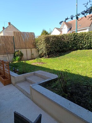 A residential backyard with a concrete staircase, a wooden bench, and a hedge.