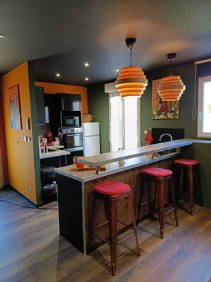 Una cocina moderna con una isla central, taburetes de bar e iluminación colgante.