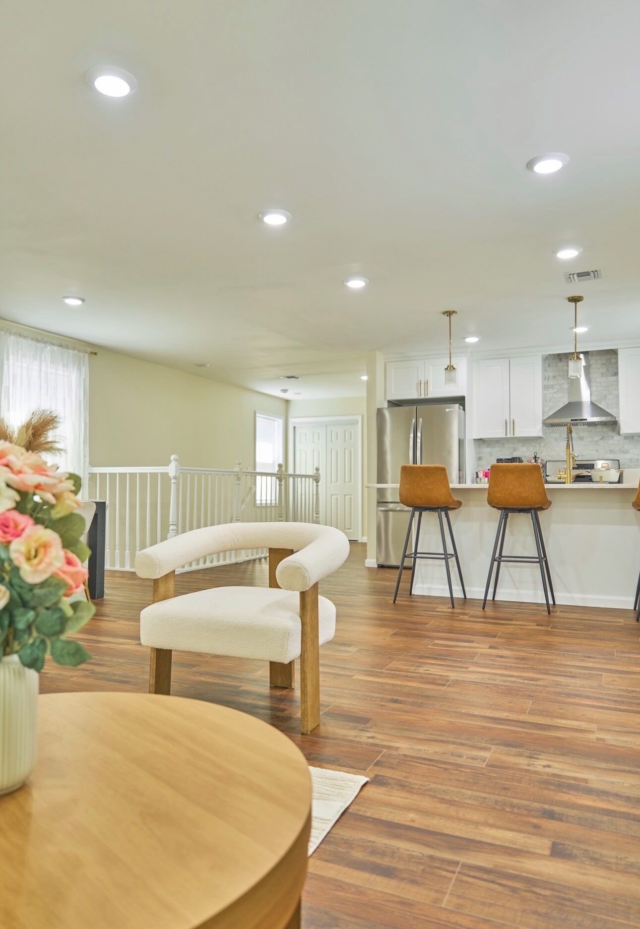 A modern kitchen with white cabinets, stainless steel appliances, and a central island with stools.