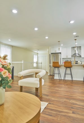 A modern kitchen with white cabinets, stainless steel appliances, and a central island with stools.