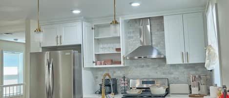 Una cocina moderna con refrigerador de acero inoxidable, doble lavamanos y una isla central con taburetes de bar.