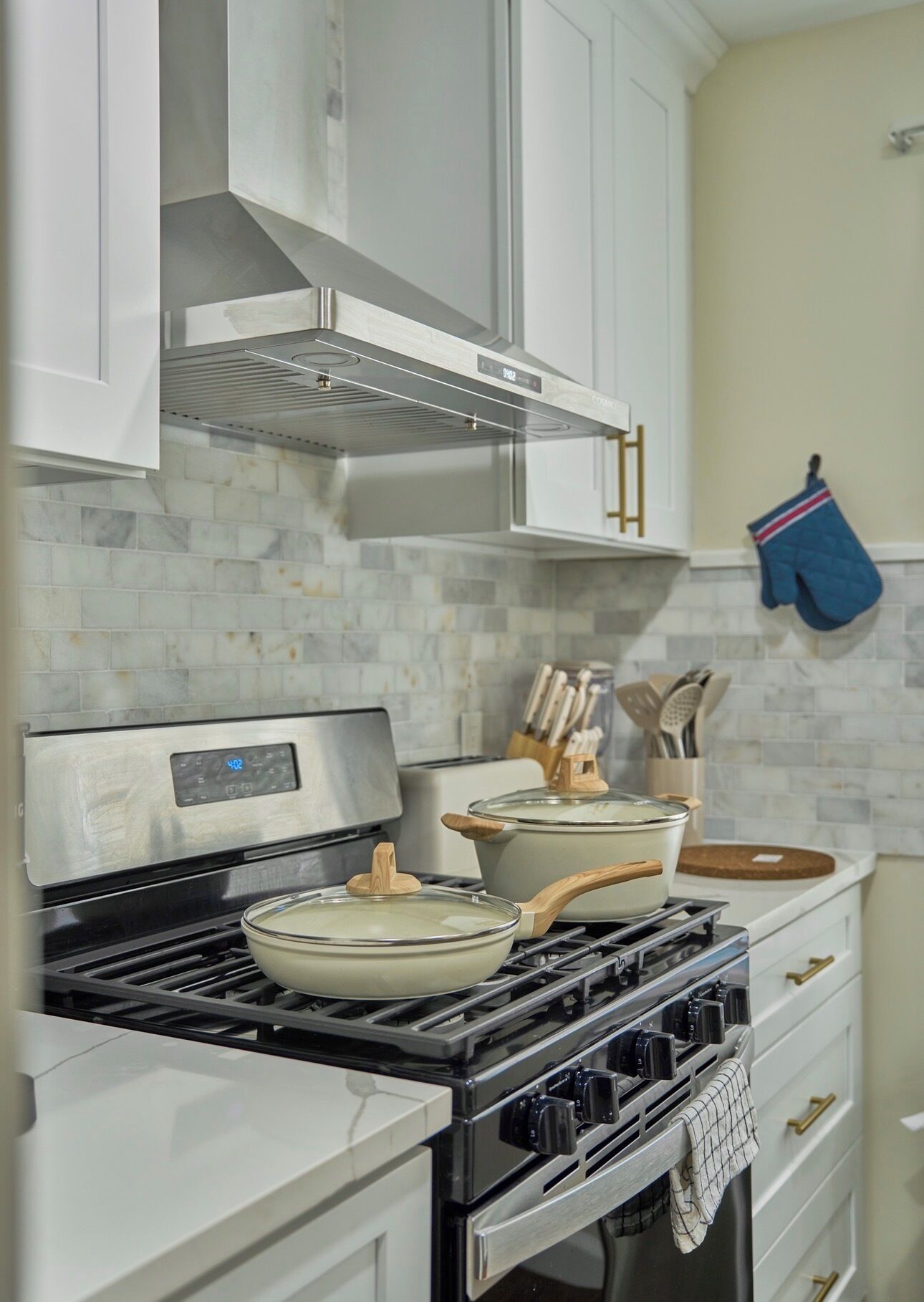 A kitchen with a stove, pots, a toaster, and a knife block.