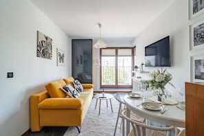 A modern living room with a sofa, dining table, and artwork on the walls.