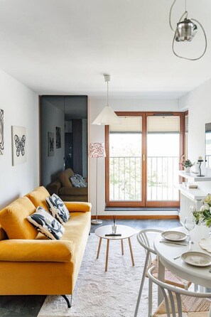 Una sala de estar moderna con un sofá, una mesa de comedor y una lámpara colgante.