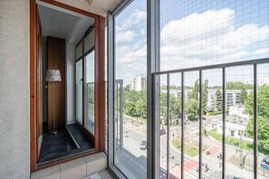 A balcony with a view of a city street, a floor lamp, and a door leading to an interior space.