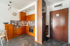 A modern kitchen with wooden cabinets, a built-in oven, and a dining area with a chair.