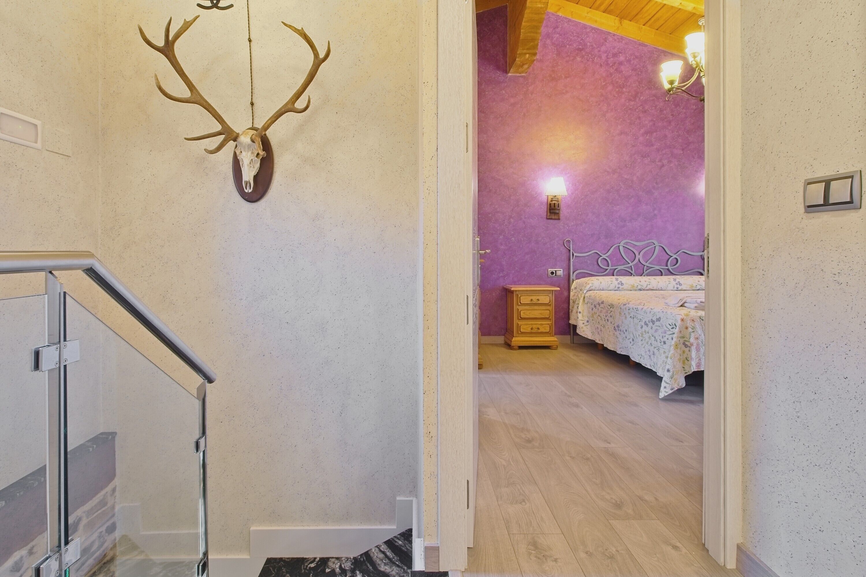 Una habitación con una cama, un aparador, un cráneo de ciervo montado en la pared y una escalera.