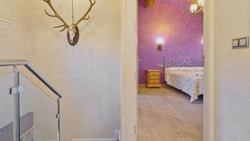 Una habitación con una cama, un aparador, un cráneo de ciervo montado en la pared y una escalera.