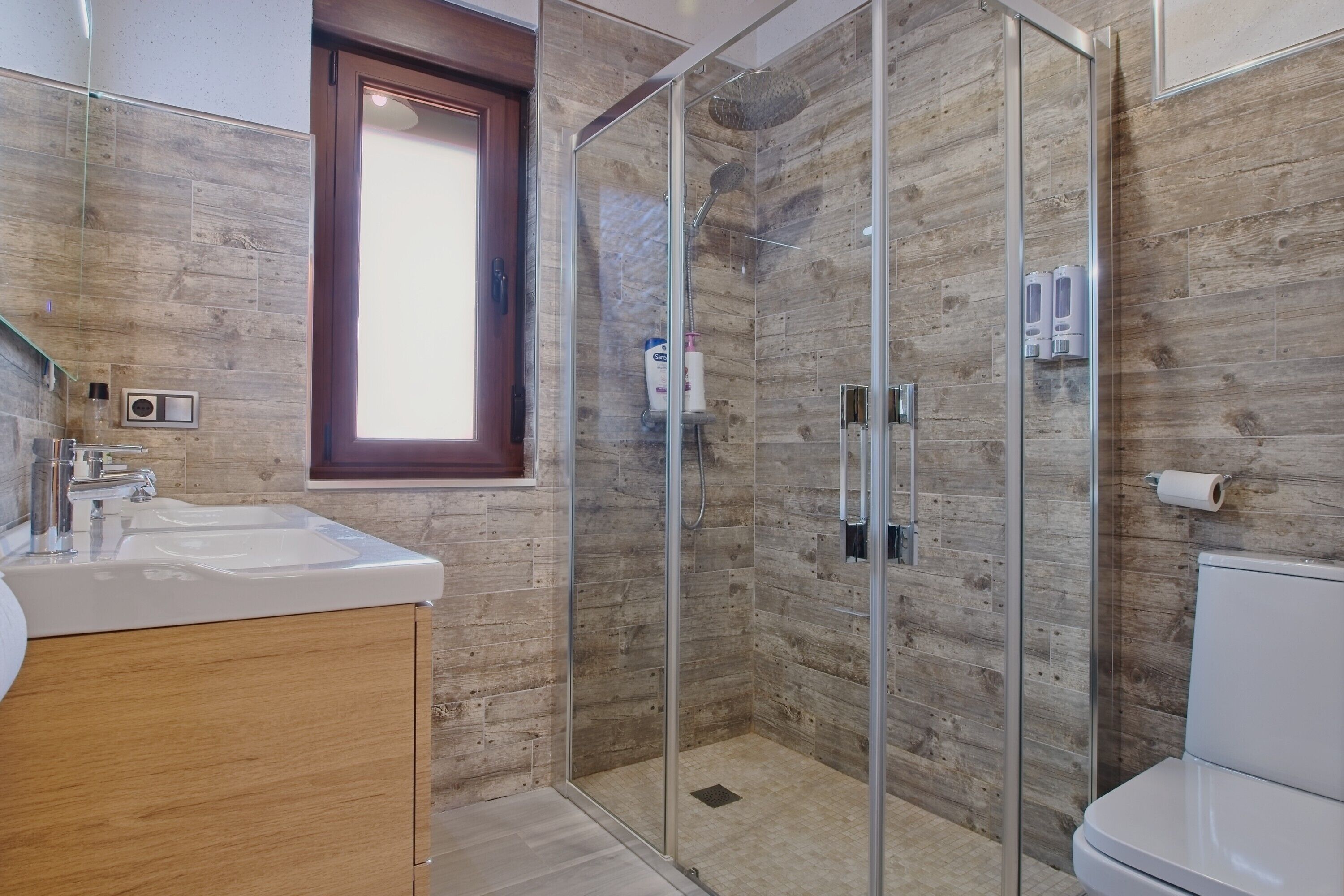 Une salle de bain moderne avec une douche à parois de verre, un meuble-lavabo en bois et des toilettes.