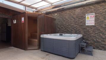 Zona de spa con jacuzzi, puertas de madera y un cartel sobre las normas de seguridad en la piscina.
