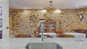 Habitación con paredes de piedra, lavamanos de granito, una mesa de comedor de madera, sillas y un candelabro.