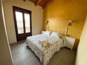 A bedroom with a bed, bedside tables, a door, and a balcony. - Casa Amada — Heated Pool, Sauna & Camino de Santiago in Astorga (Pedredo)