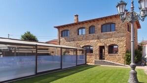 Un edificio de piedra con un área de estar cubierta al aire libre y un césped bien cuidado.