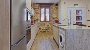 Una cocina compacta con pared de piedra, lavadora y lavamanos.