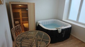 Ein Zimmer mit einem Glastisch, einem schwarz-weißen aufblasbaren Bett und einem Holzkasten.