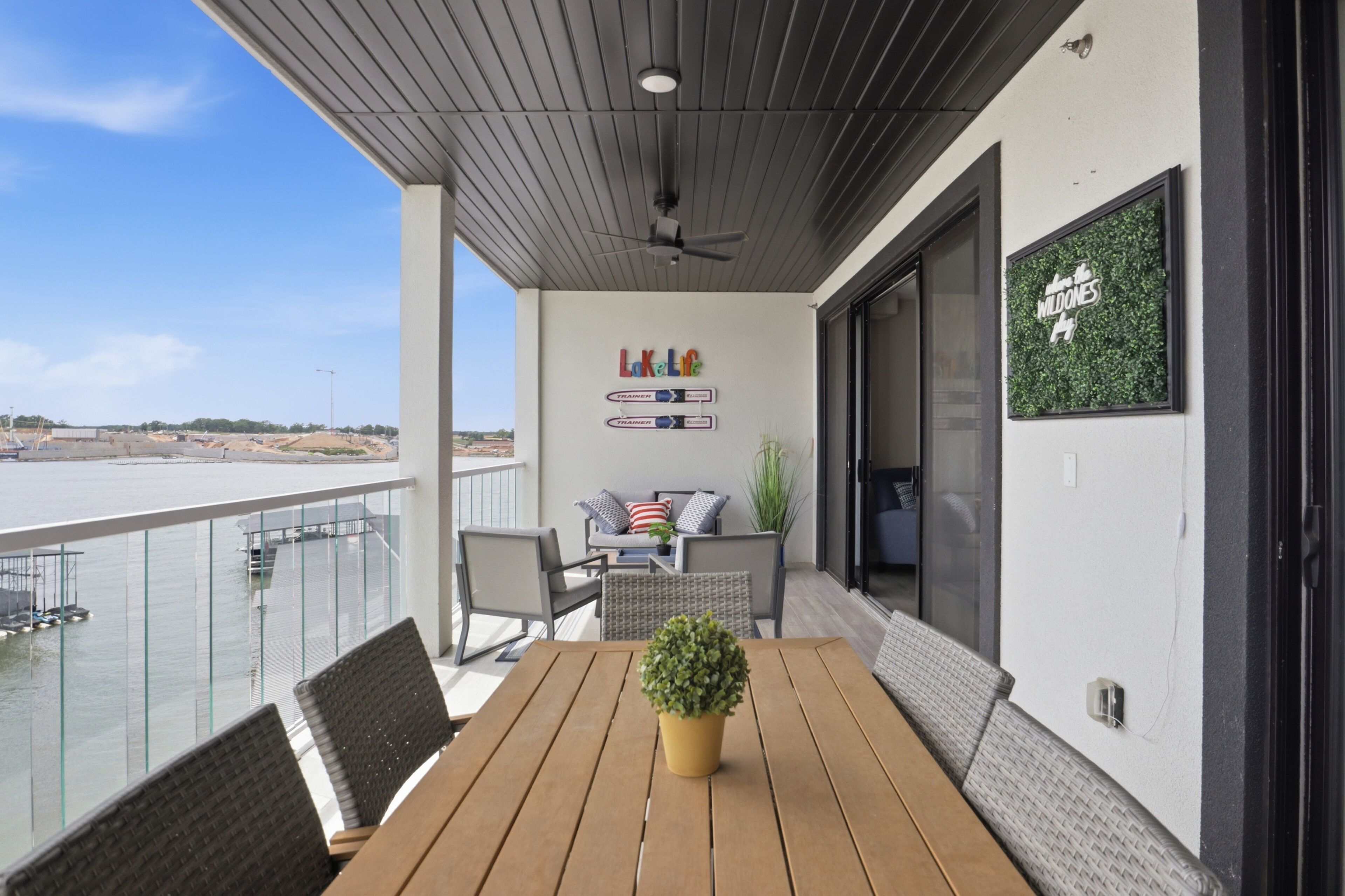 Ein Balkon mit einem Holztisch, Stühlen, einem Blumentopf und einem Schild mit der Aufschrift 'Lo Caliente'.