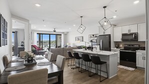 Una cocina moderna con una isla central, sillas negras y una zona de comedor con mesa y sillas.