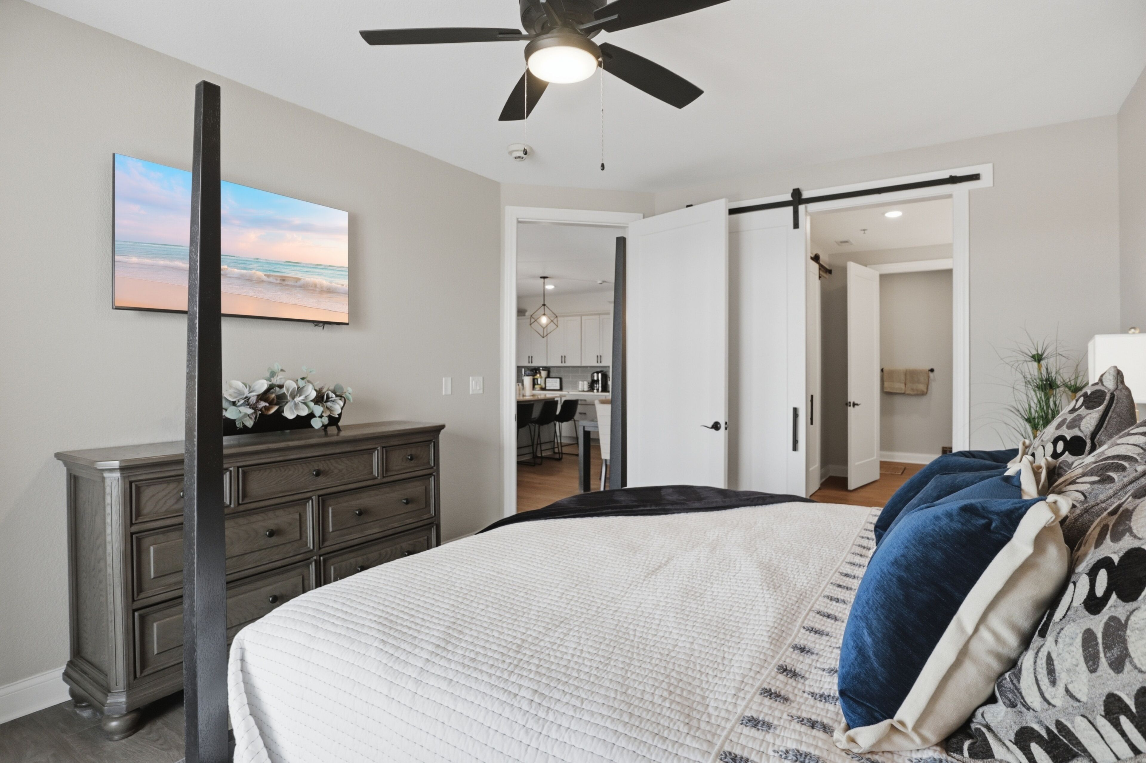 Ein Schlafzimmer mit Bett, Kommode und Deckenventilator.