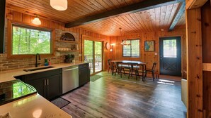 Interior de madera con cocina, comedor y una puerta con símbolo de cruz.