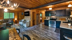 Un amplio salón con chimenea, una mesa de comedor y una cocina equipada con electrodomésticos modernos.