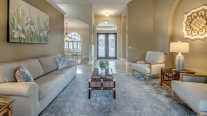 A spacious living room with a sofa, armchair, coffee table, and decorative items. - Heated Pool - Spacious - Bike - BBQ- Sound System (Cape Coral)