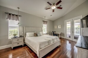 Un dormitorio con cama, mesitas de noche, un escritorio y un ventilador de techo.
