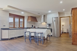 A modern kitchen with a central island, built-in appliances, and a dining area with bar stools.