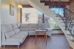 Ein Wohnzimmer mit Ecksofa, einem Holztisch und einer Treppe mit aufwendiger Metallgalerie.