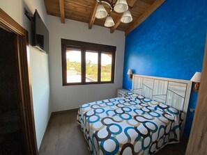 Un dormitorio con cama, ventana, televisor y ventilador de techo.