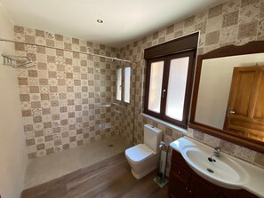 Un baño con baldosas estampadas, un inodoro, un lavabo y una ventana con espejo.