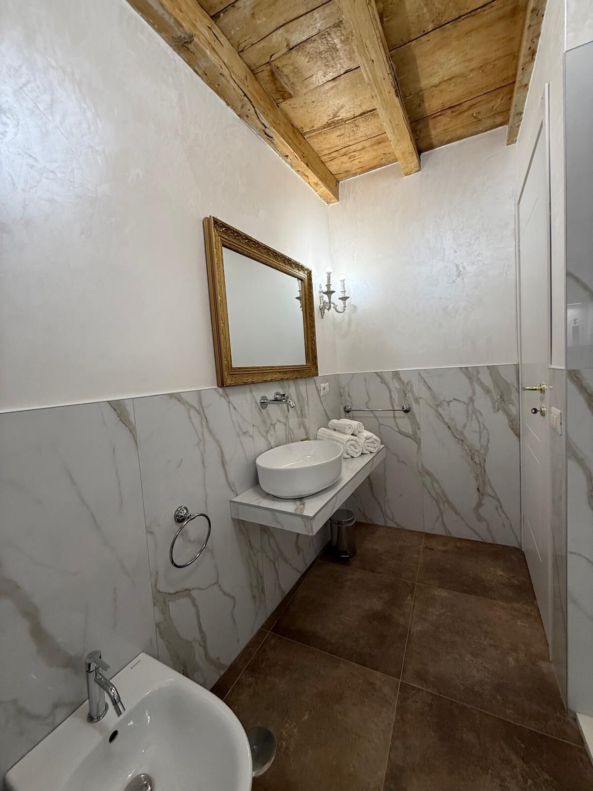 Een badkamer met een marmeren wastafel, een wastafel, een badkuip en een houten plafond.