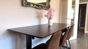 Une table à manger avec des chaises, un vase rempli de fleurs et un miroir accroché au mur.