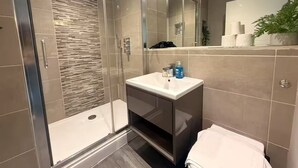 Une salle de bain moderne avec une douche à parois de verre, un meuble-lavabo avec un miroir et des toilettes.