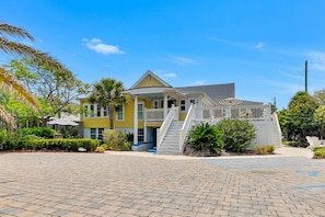 A two-story building with a porch, a staircase, and a pool area. - The Georgianne Manor (Tybee Island)