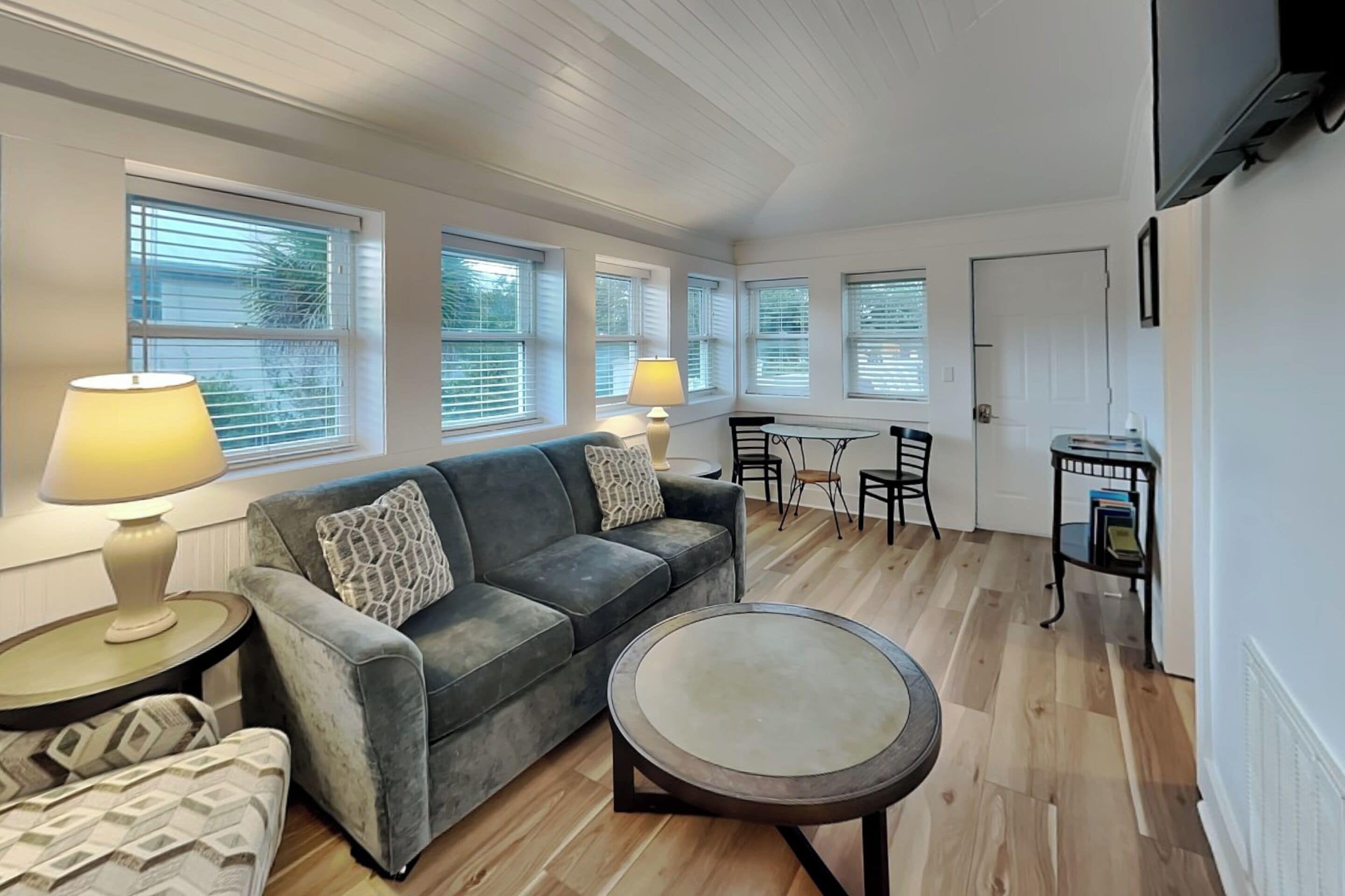 A living room with a sofa, a coffee table, and a dining area with chairs and a table.