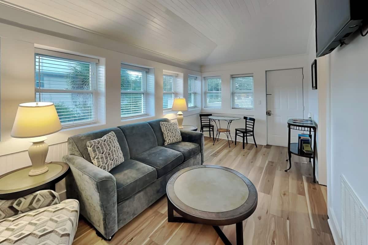 A living room with a sofa, a coffee table, and a dining area with chairs and a table.