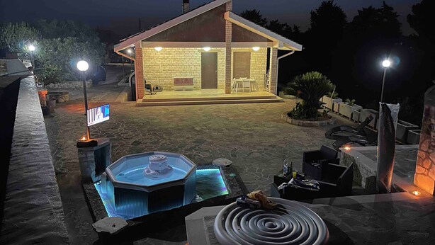 Une maison avec un patio, un jacuzzi et un espace salon extérieur.