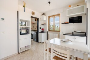A modern kitchen with white cabinetry, a built-in microwave, and a window overlooking a scenic view. - Happy's Casa: Experience the Countryside 20 Minutes from the Sea (Putignano)